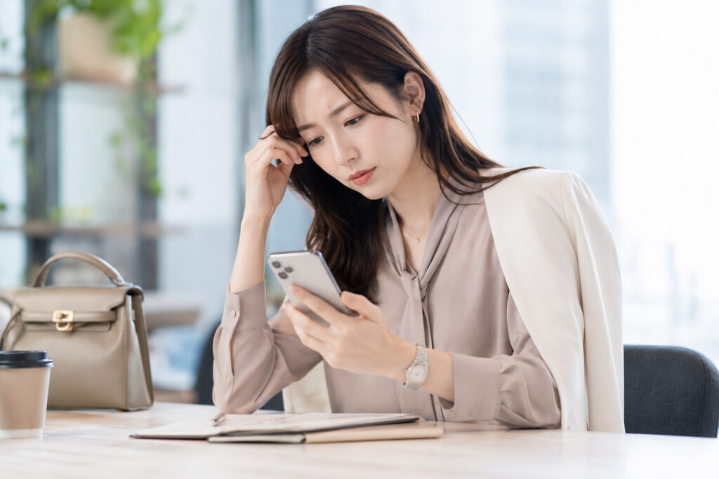 スマホを見て悩む女性